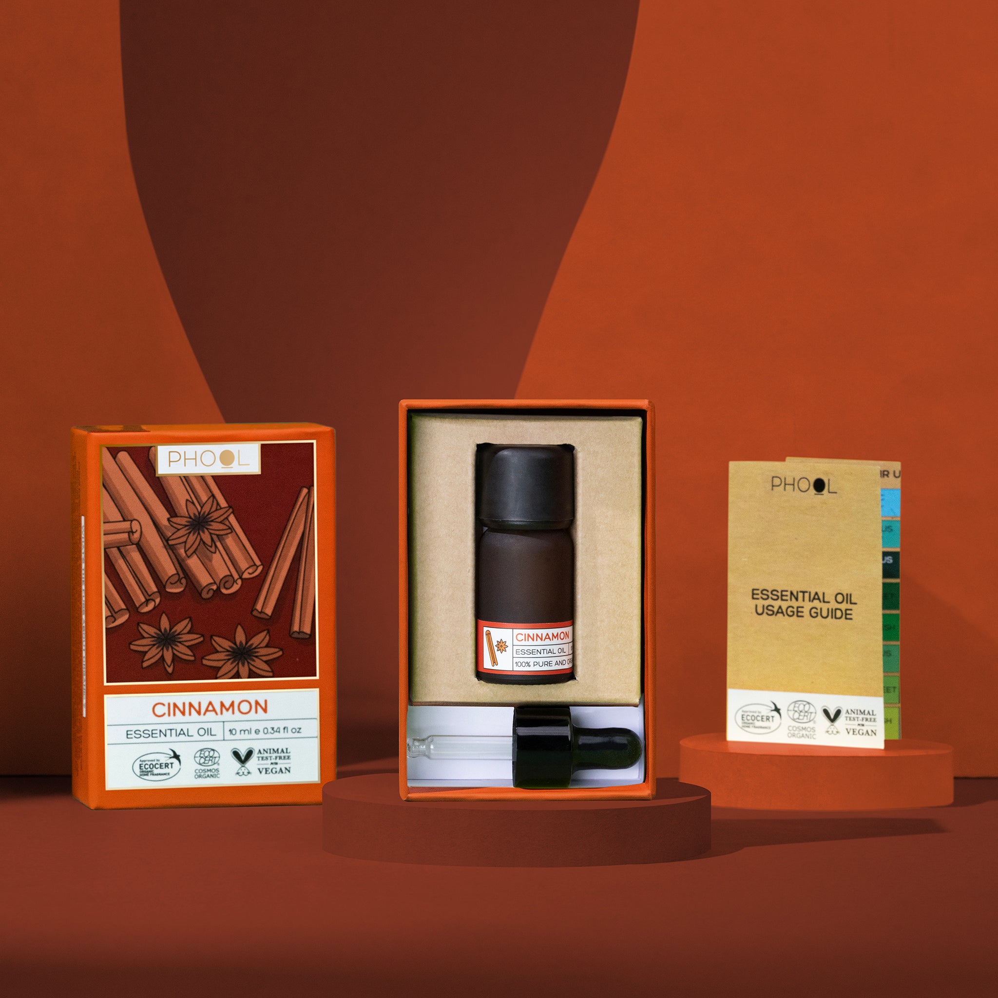 Phool Cinnamon Essential Oil set with bottle, dropper, outer packaging, and a usage guide on an orange background.