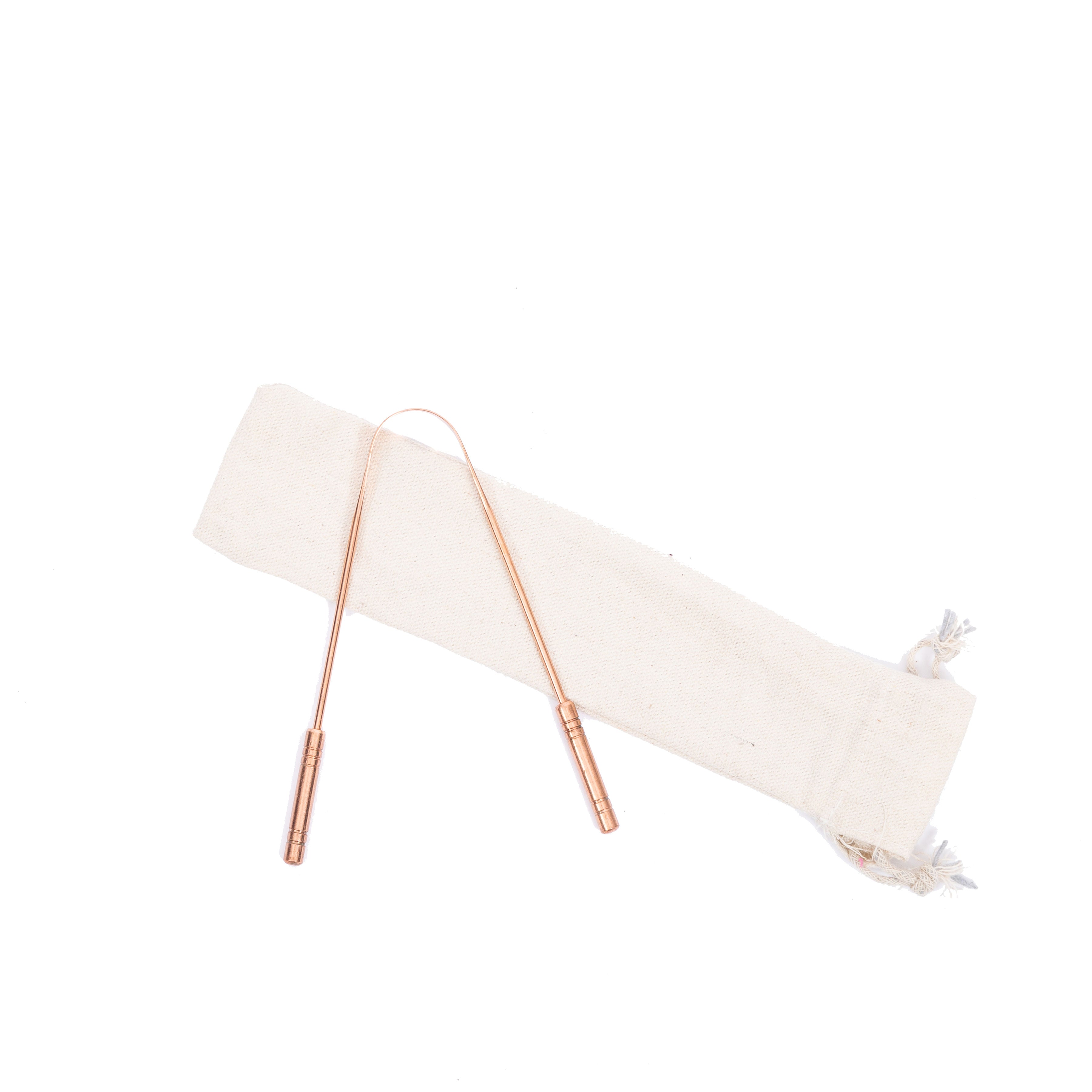 MSY copper tongue scraper resting on cream cotton bag on a white background.