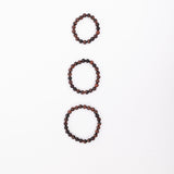 Small, medium and large Tiger Eye Mala Bracelets on a white background, ordered from small to large vertically.