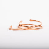 Three slender, open-ended Maya Shanti Yoga Copper Bracelets stacked together, interlocking, on a white background.