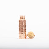 Maya Shanti Yoga Copper Hammered 750ml Water Bottle with wooden list resting next to it on a white background.