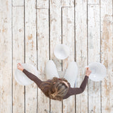 Top view of a person on a wooden floor holding two Maya Shanti Yoga MSY Crystal Singing Bowls (432 Hz), part of a 3-piece set, with the third bowl nearby, preparing for a serene sound healing session.