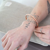Person's forearm wearing the Maya Shanti Yoga Copper Bracelet, resting on a MSY yoga cushion.