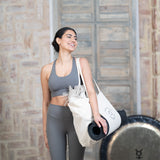 A woman holding a MSY Yoga Totebag - Cotton from Maya Shanti Yoga, representing wellness.