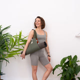 Woman smiling away from the camera wearing grey gym wear and a MSY Mat Baguette over her right shoulder.
