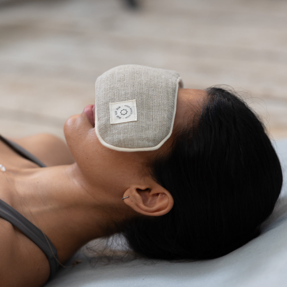 A person lying down with a beige eye mask covering their eyes.