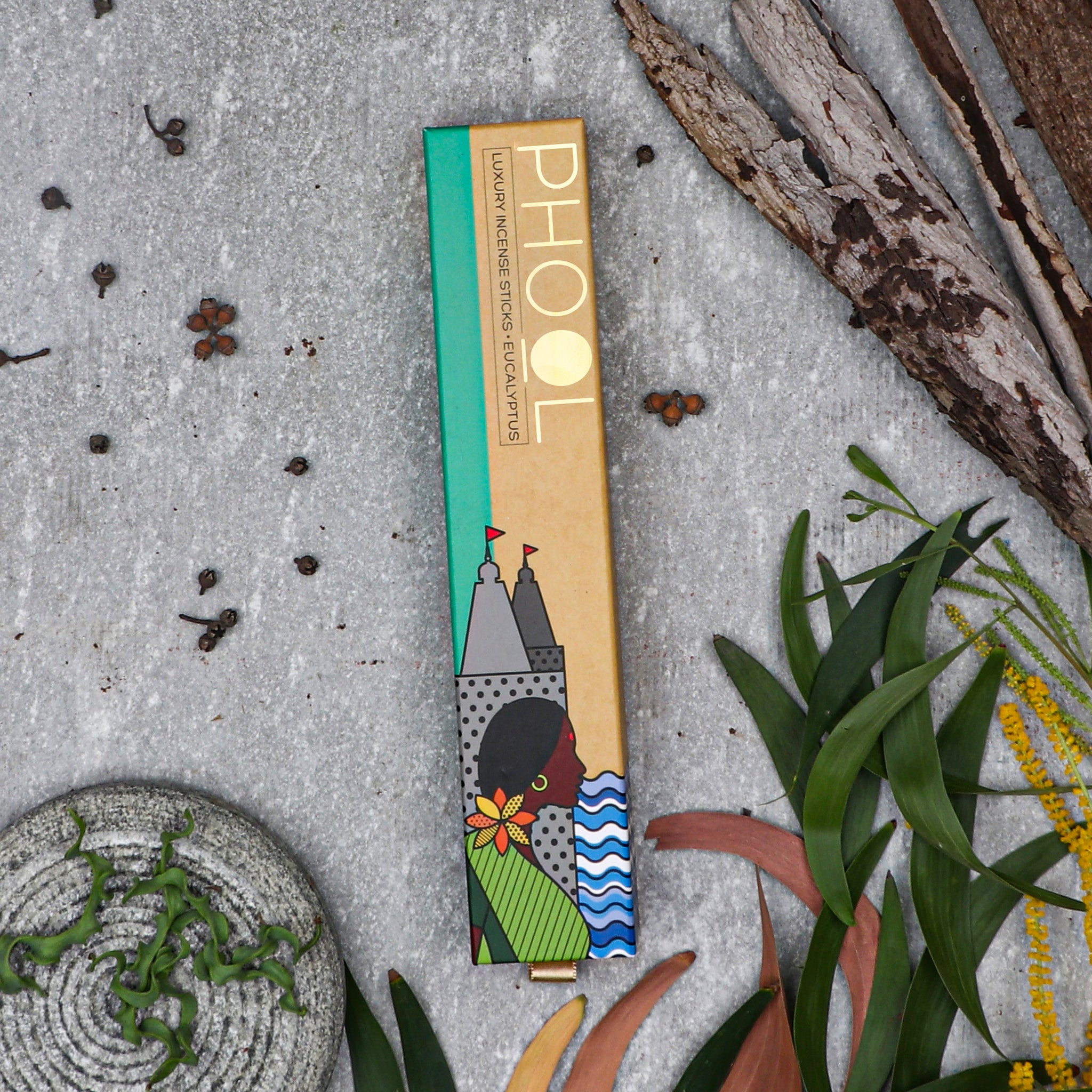 Eucalyptus incense sticks on a textured surface with plants and leaves.