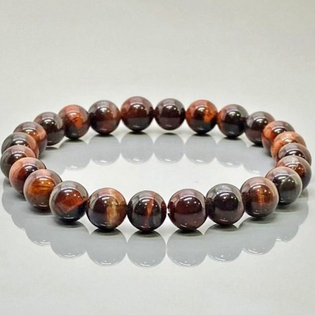 Tiger Eye bracelet with brown and red stones on a reflective surface