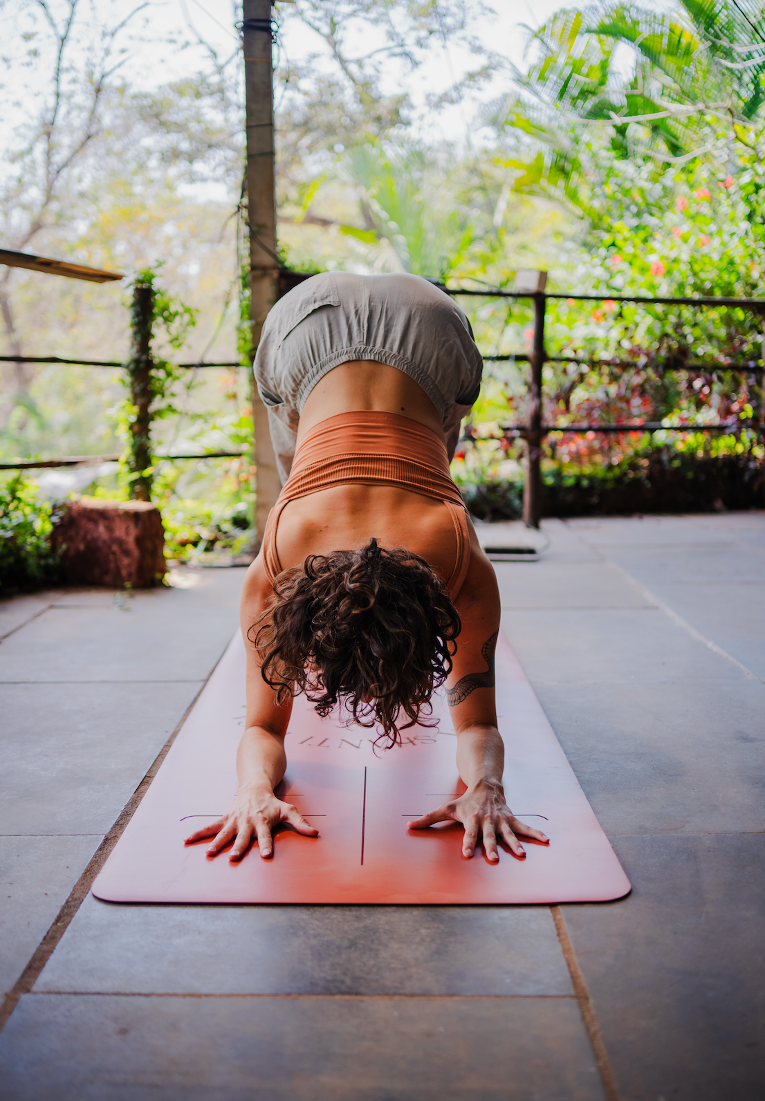 Person performing a yoga pose on a mat against a brick wall.