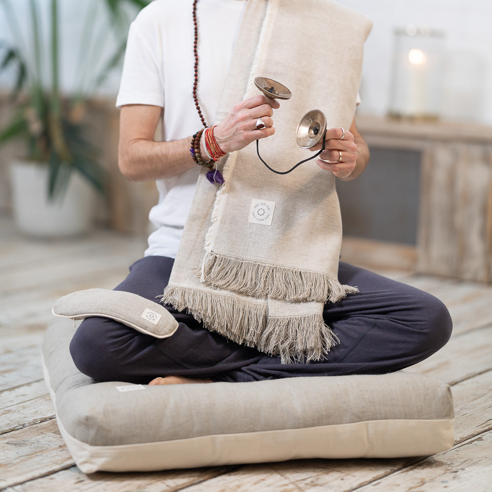 A man practicing mindfulness and meditation on a MSY Zabuton - Meditation Cushion - Hemp & Organic Cotton from Maya Shanti Yoga, in the pursuit of wellness.