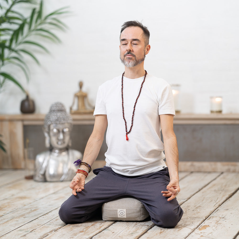 A man practicing mindfulness while meditating in front of a Maya Shanti Yoga Mala Meditation Beads Rosewood.