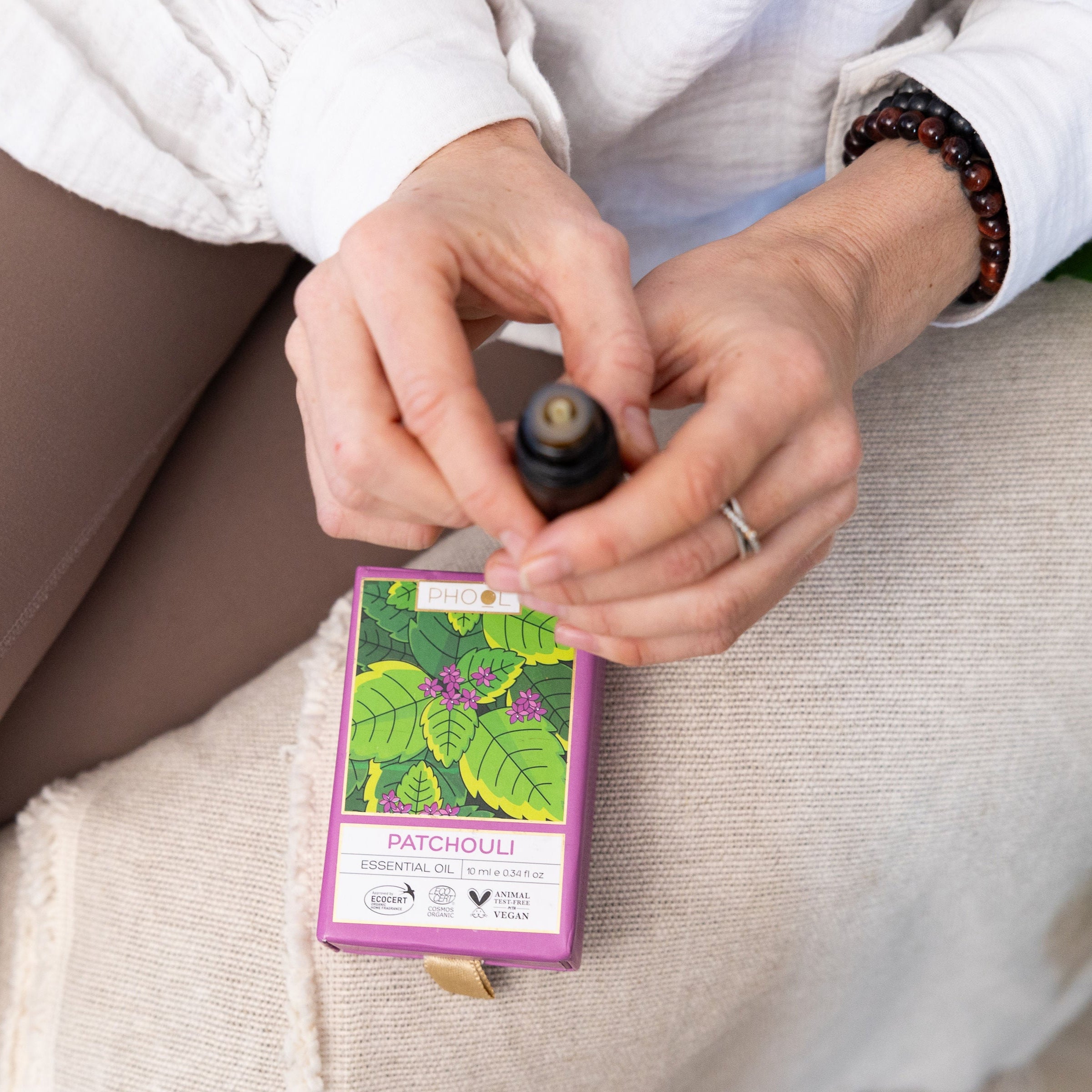 Person holding a bottle of Patchouli essential oil with a matching box.