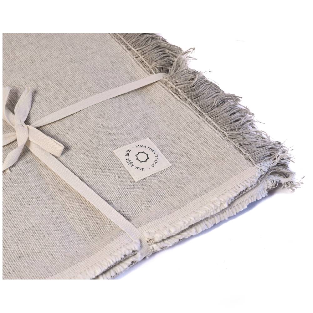 Folded MSY Meditation Yoga Blanket - Hemp & Organic Cotton napkins with fringe, made from sustainable materials, tied with a ribbon, featuring a sewn label with a llama motif and text. (Brand Name: Maya Shanti Yoga)