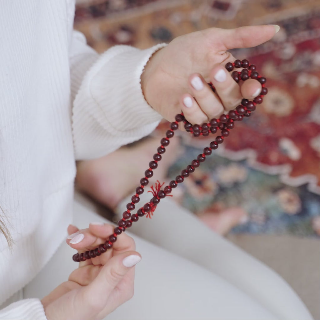 Video of a woman handling a red Maya Shanti Yoga Mala Meditation Beads Rosewood while practicing meditation.