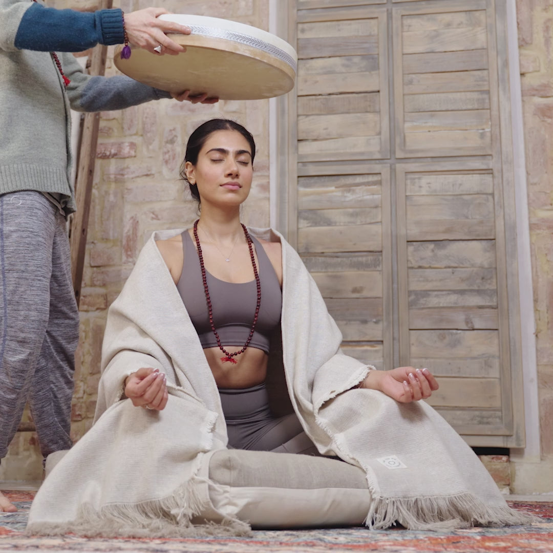 A video of a man practicing mindfulness and meditation, using a Maya Shanti Yoga 18inch Ocean Drum around a woman sitting in the floor.