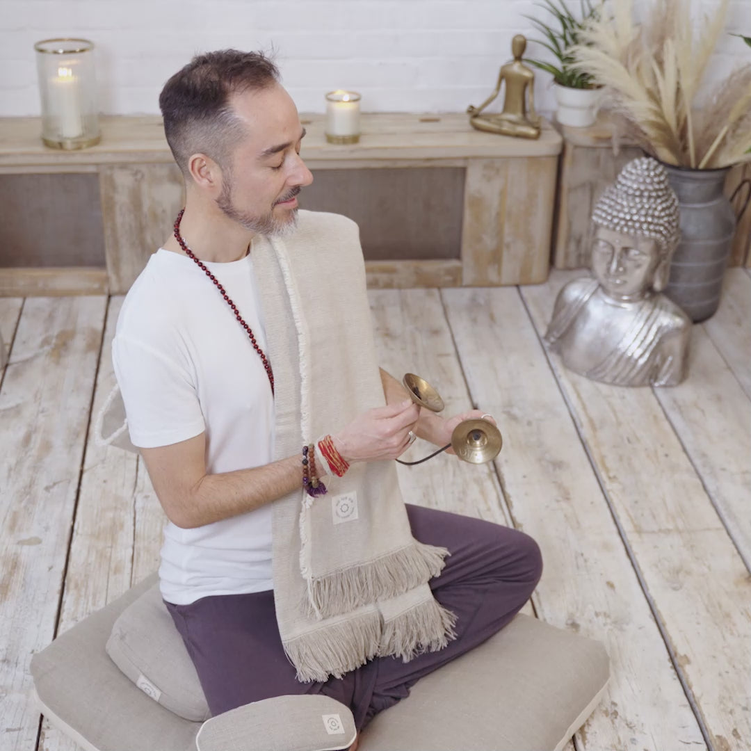 A video of a man using a set of MSY Serenity Bundle including small bolster, zabuton, blanket and eyepillows on a white surface, perfect for mindfulness and meditation, by Maya Shanti Yoga.