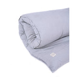 A grey MSY Shiatsu Meditation Bed - Organic Cotton resting peacefully on a white background for enhanced mindfulness and wellness by Maya Shanti Yoga.